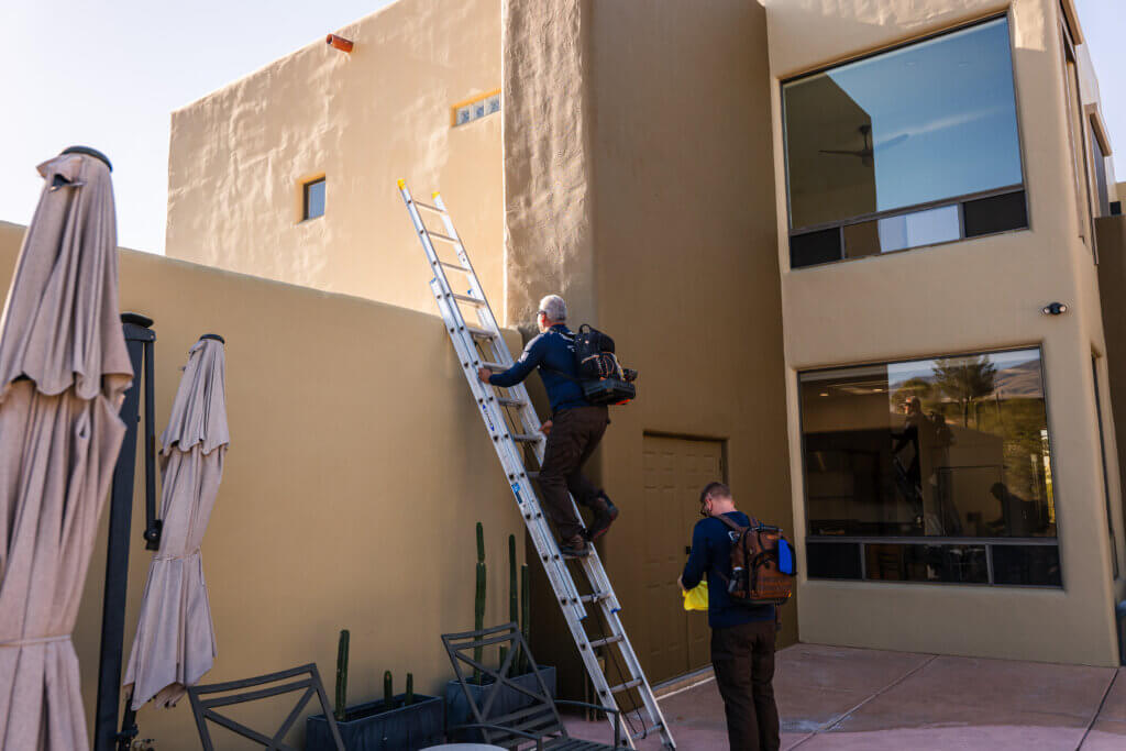 Air conditioning service Tucson technicians using a ladder to access rooftop HVAC equipment for professional maintenance, inspection, and repair.