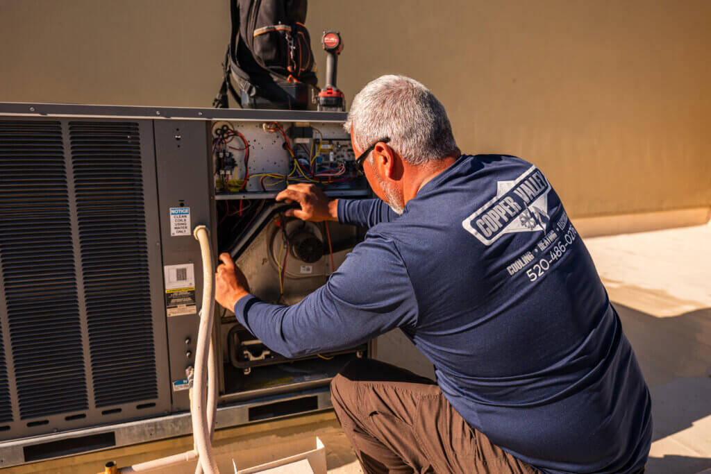 Air conditioning Tucson technician measuring system performance with HVAC diagnostic tools.