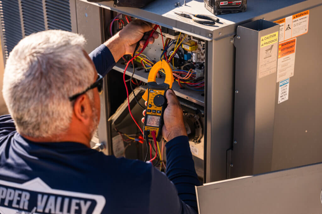 Experienced Tucson A/C repair specialist testing HVAC electrical connections during a residential service appointment.