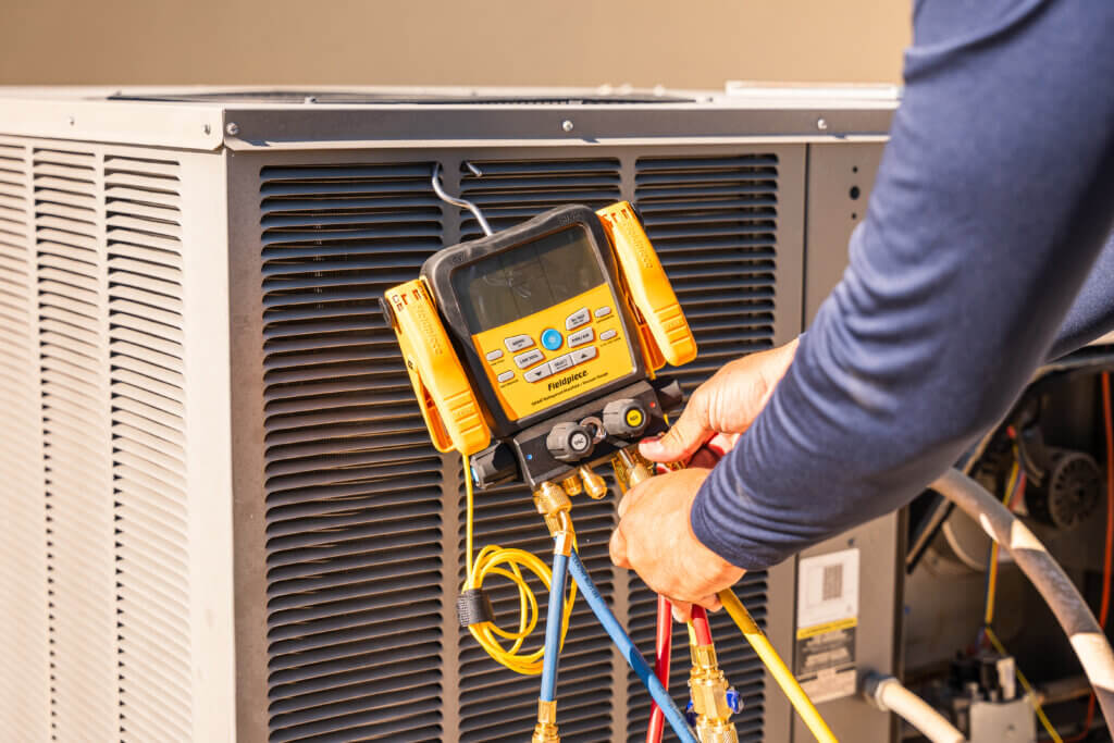 Air conditioning Tucson technician measuring system performance with HVAC diagnostic tools.