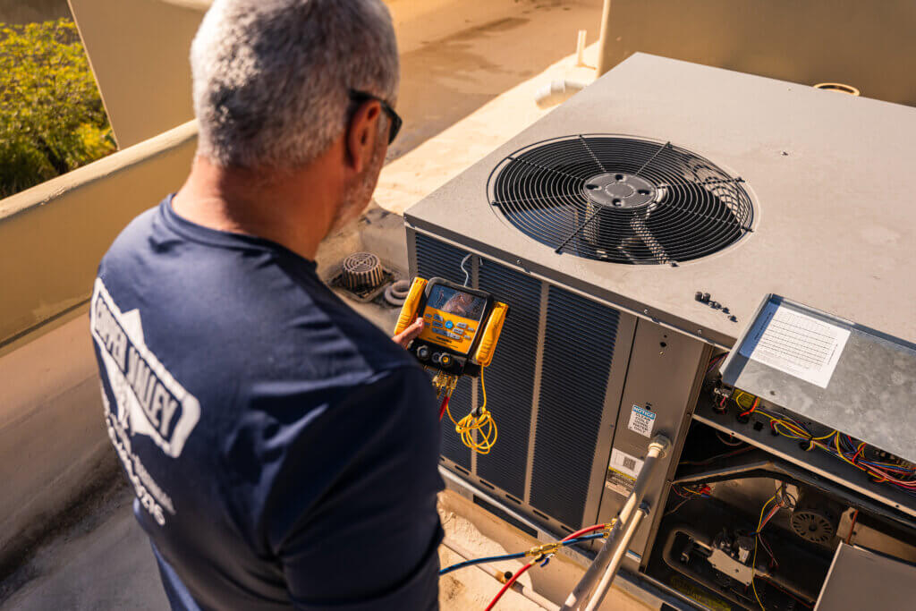 Tucson HVAC contractors using advanced diagnostic equipment to inspect an outdoor HVAC unit.