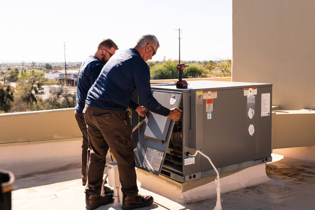 Technicians performing Tucson air conditioner repair on a rooftop HVAC unit to restore efficient cooling and system performance.