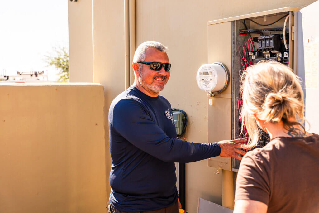 Tucson HVAC contractor speaking with a customer while inspecting residential heating and cooling equipment.