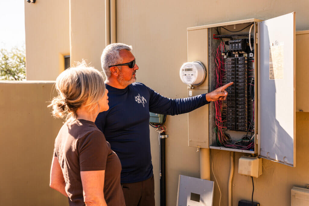 Tucson air conditioner repair technician explaining electrical components and repair recommendations to a homeowner during an HVAC service visit.