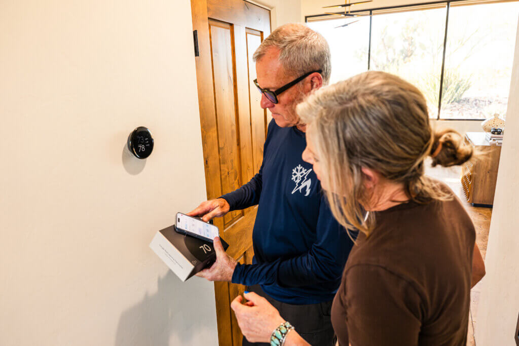 Representative from one of the trusted HVAC companies Tucson homeowners rely on reviewing thermostat settings and system performance with a customer.