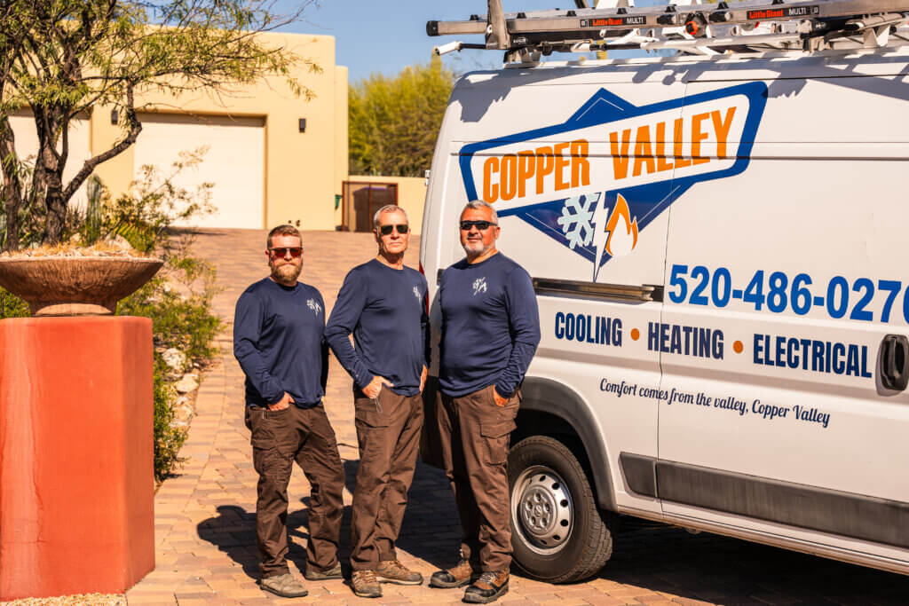 HVAC Tucson AZ service technicians standing beside a branded company vehicle, ready to provide professional heating and cooling services.