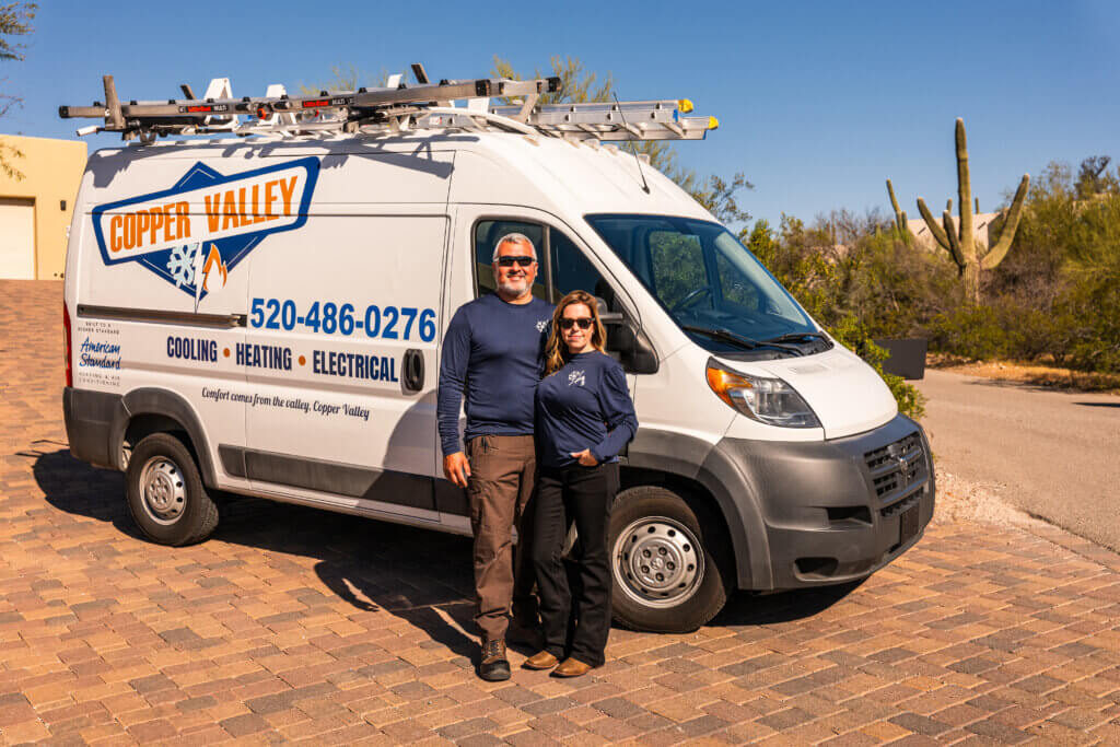 HVAC Tucson AZ service professionals standing in front of a branded company van, ready to provide expert heating and cooling solutions.